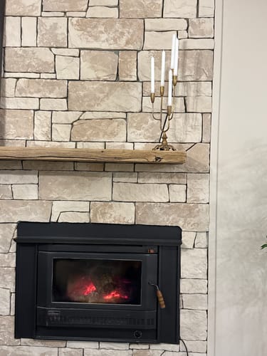 Customer's antique gold Lisette Candelabra with white taper candles on a wooden mantel above a fireplace.