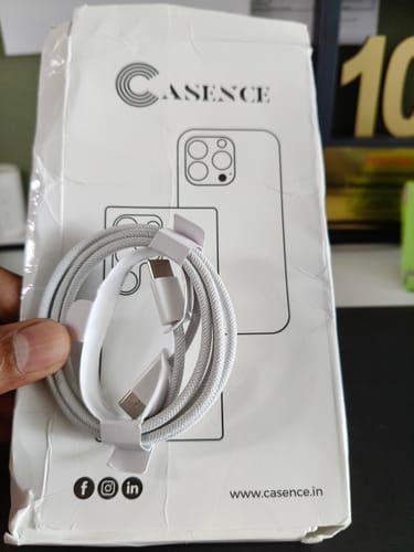 Customer holding the coiled, braided Casence Armor Type C to C cable in front of its packaging.