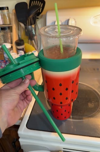Reviewer holds the lid of a Watermelon Kiss Thicc Buddy, showing it being used as an insulator for a separate cup.