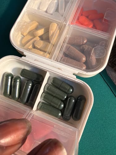 Customer's pill organizer showing dark green Body Magic Chlorophyll Pills alongside other daily supplements.