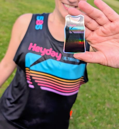 Reviewer holding a holographic Cut to Shape Sticker that matches their tank top.