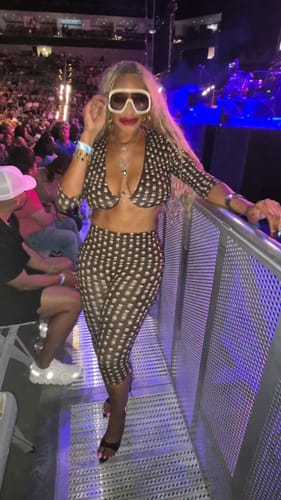 Customer wearing the Naked Print Capri Legging and matching top at a concert, posing with sunglasses.