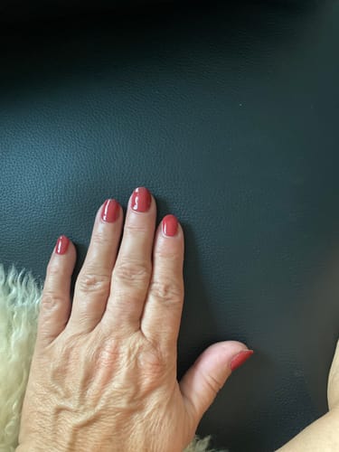 Bewertung einer Kundin: Hand mit roten Nägeln und glänzendem Finish durch den UV Top Coat.