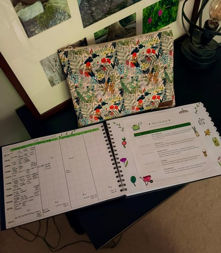 Reviewer's Madre's Flower Garden Pouch sitting on a desk next to an open, handwritten planner.