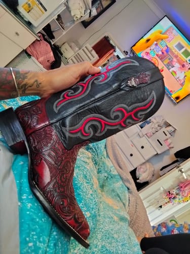 A customer holds up their new Ace Of Spades boot, showing the red tooled foot and black embroidered shaft.