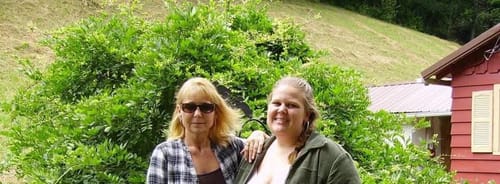 Reviewer and another person posing for a photo outdoors in a garden setting.