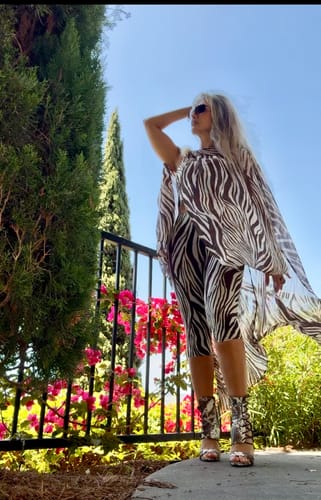 Side view of the reviewer wearing the Naked Print Ruched Tube Top with a matching flowing cape.