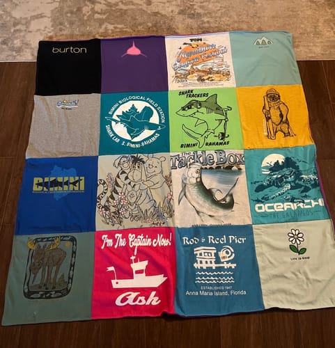 Customer's colorful Project Repat T-Shirt Quilt featuring various graphic prints laid flat on a brown floor.