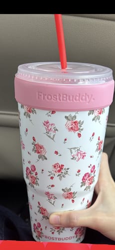 Customer's Pink Floral To-Go Buddy tumbler held in hand with a straw in a car cup holder
