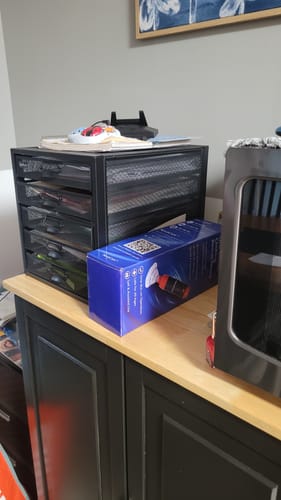 Customer's NovaCare Anti-Choking Device box resting on a wooden surface next to a black organizer drawer.