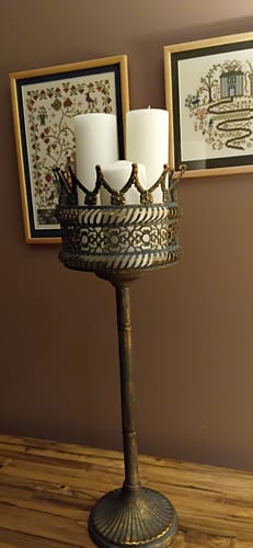 Customer's Solange Crown Pedestal Planter Stand holding white candles, placed on a surface in front of wall art.