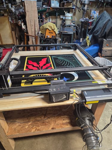 Customer's AtomStack A70 Max laser cutter positioned on a wooden table with colorful engraved boards.