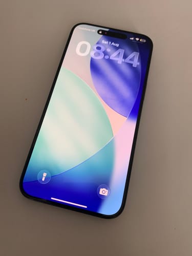 Customer's Apple iPhone 15 Pro Max displaying the lock screen with a clear, colorful wallpaper.