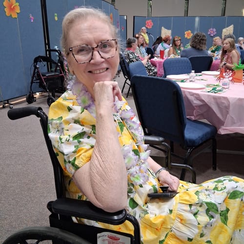 Customer's smiling person in a floral dress, showcasing skin progress on their neck.