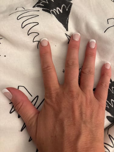 Reviewer's hand showing a fresh set of Holy Gels with a clean french manicure finish.