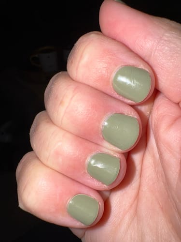 Customer's hand showing smooth, glossy sage green nails applied with the Holy Gels Starter Kit.