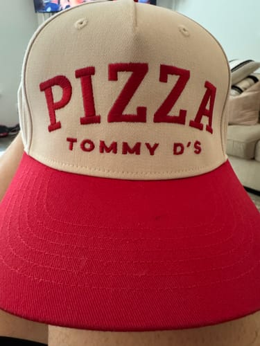 Customer's beige custom embroidery hat with red PIZZA TOMMY D'S text and a red brim.