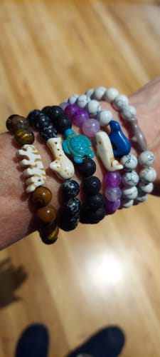 Customer's wrist wearing The Prowl Bracelet alongside several other colorful bead bracelets.