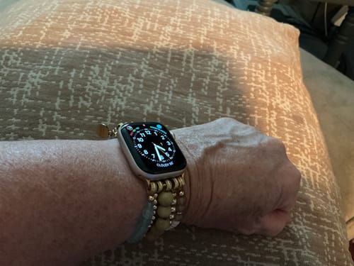Customer's Apricot Mist Stretch Apple Watch Strap worn on a wrist with neutral beads and a digital watch face.