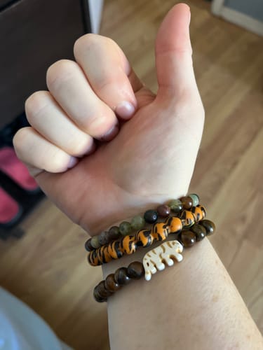 Customer's Prowl Bracelet on a wrist, featuring tiger-striped beads and a tiger charm.