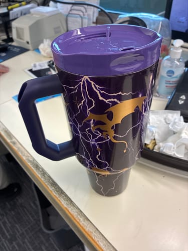 Customer's purple Thicc Buddy 50oz mug featuring a gold dragon and white lightning print sitting on a desk