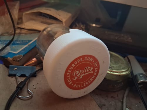 Customer's CALI MIX AAA+ storage jar with a white lid and orange label, sitting on a cluttered surface.