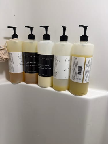 Customer's collection of five Conditioner bottles lined up on a shower ledge.