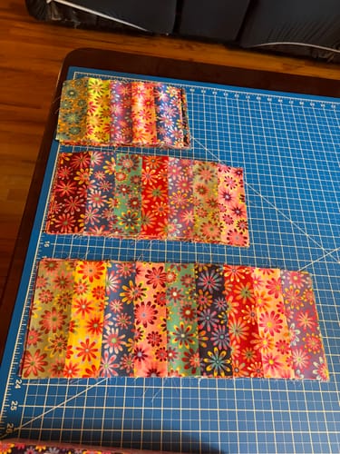 Customer's Crazy Daisy Pre-Cut Quilt Kit with floral fabric strips laid out on a blue cutting mat.