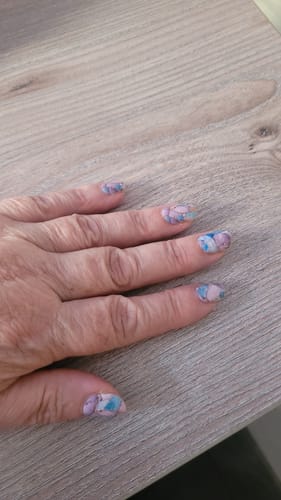Reviewer's hand showing Skipping Stones nail stickers on nails against a wooden surface