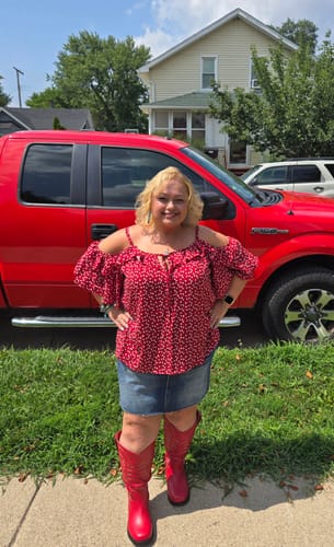 Customer's Judy Blue denim skirt worn with a red top and boots, standing outdoors in front of a red truck.