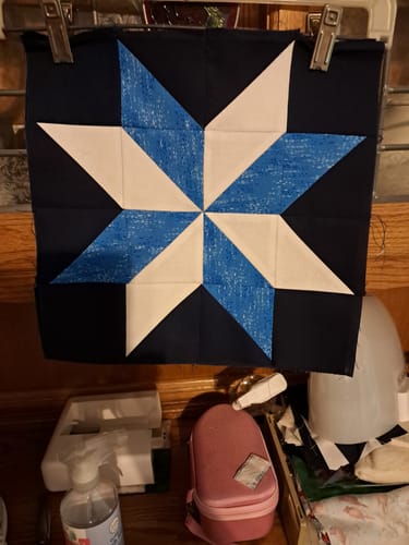 Customer's Snow Much Fun quilt block featuring a blue and white star pattern on a dark background.
