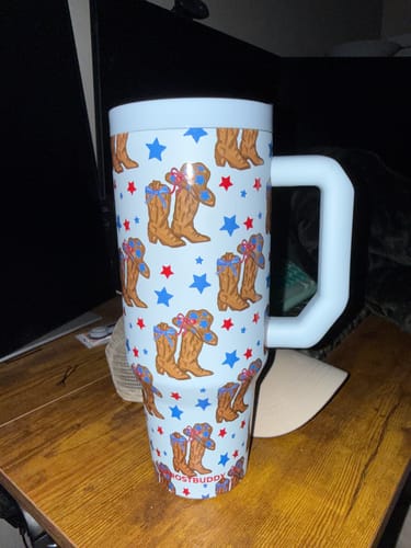 Customer's Thicc Buddy 40oz mug featuring a light blue western pattern of cowboy boots and hats with stars on a wooden surface.