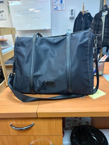 Customer's black Bolso Nylon Notebook Office Iconicas sitting on a wooden office desk.