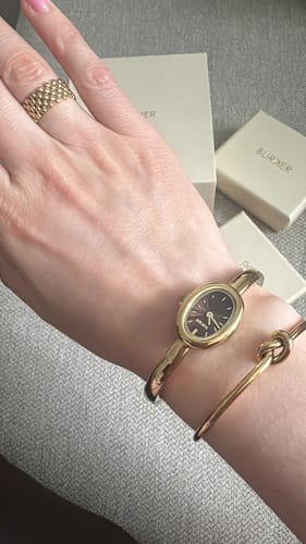 Customer's gold Eternity Gold Bracelet worn on wrist alongside a watch, showing a minimalist knot style.