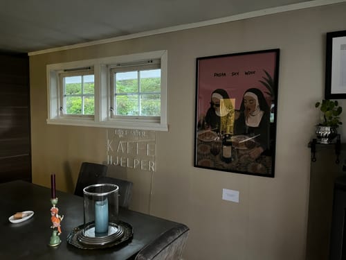 Customer's HOLY TRINITY framed art print hanging on a dining room wall, next to a window.