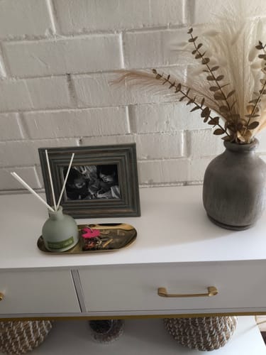 Customer's Marco De Fotos Boho placed on a white table next to a decorative vase and reed diffuser.