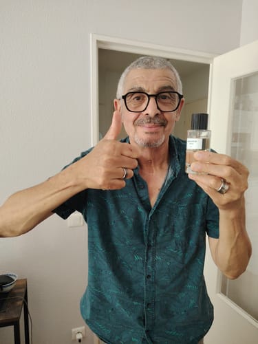 Client tenant le parfum HPR3 dans sa main tout en faisant un geste de pouce levé.