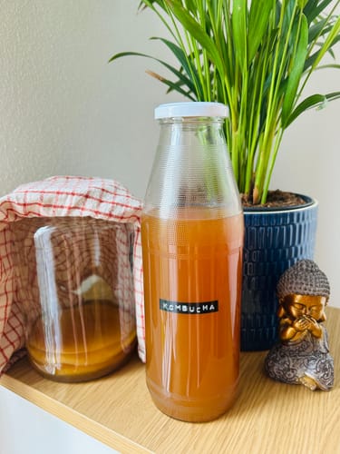 Kundenfoto des Kombucha Starter-Set mit einer Flasche Kombucha und einem Glasgefäß mit Fermentationsansatz.