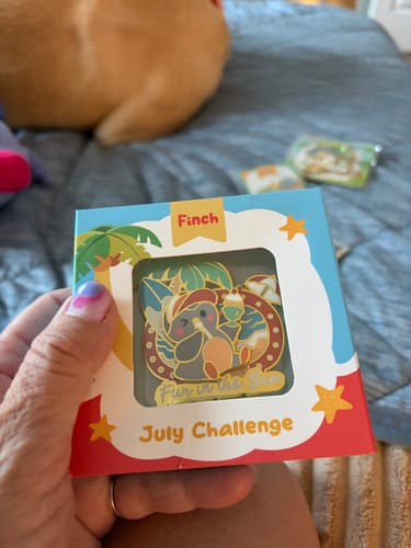 Customer's Fun in the Sun Pin inside its colorful July Challenge packaging held by a hand.