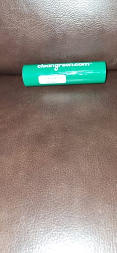 Customer's green cylinder packaging for the Mystery Gift, resting on a brown leather surface.