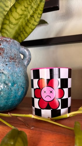 Reviewer's Sad Flower Kokosnuss Rose Statementkerze with checkerboard pattern and flower motif on a wooden shelf.