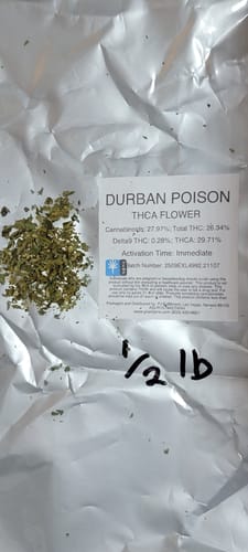 Customer's Durban Poison THCA flower with a label on a white surface, next to a small pile of loose product.