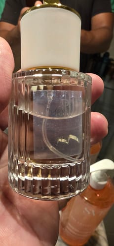 Main d'un client tenant une bouteille en verre HYS1 transparente et côtelée avec un bouchon doré.