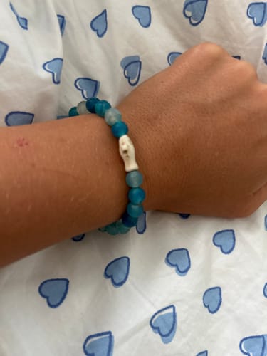 Customer's Voyage Bracelet featuring blue beads and a white shark charm worn on a person's wrist.