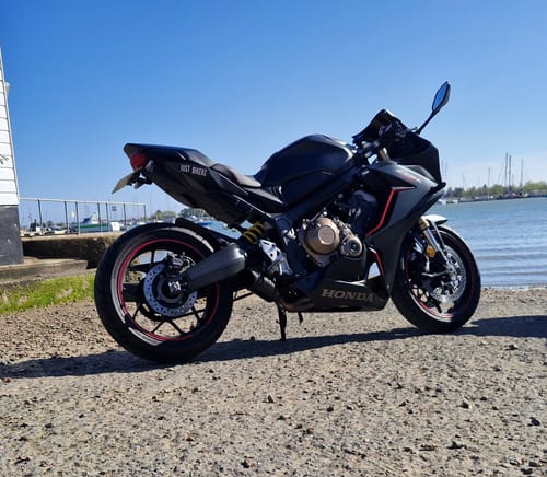Customer's Honda CBR650R showing the installed low-profile tail tidy, parked outdoors near water.