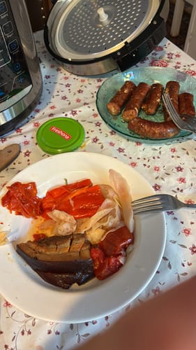 Reviewer's set of 100 hartii de copt, with a liner holding cooked food on a white plate next to sausages