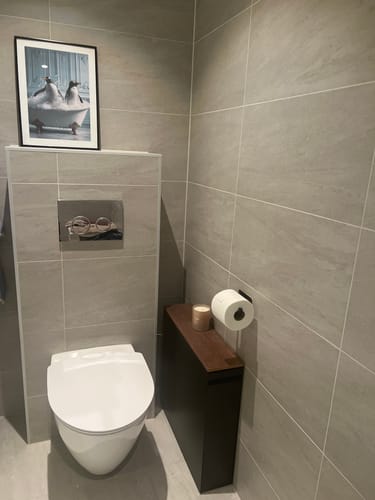 Customer's sort uttrekkbar oppbevaringshylle plassert mellom toalettet og veggen på et bad.