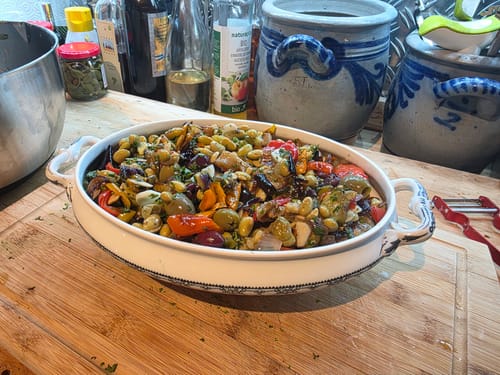 Customer's Kümmel Bioproduct used as a flavorful spice in a colorful, vegetable-filled casserole dish on a wooden board.