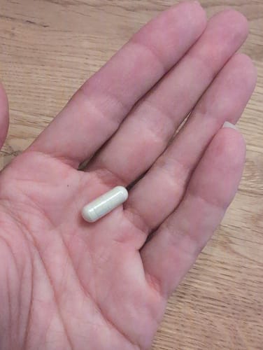 Reviewer's hand holding a single light-colored Bosvera capsule