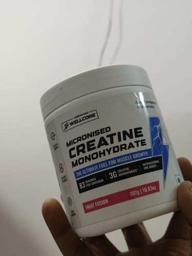 Customer's hand holding a jar of Wellcore Micronised Creatine Monohydrate in Fruit Fusion flavor.